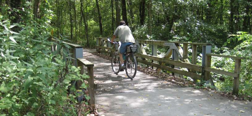 Cyclist crossing a wooded boardwalk bridge on the Fairfield Loop Trail